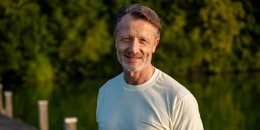 Happy senior man in white t-shirt near lake