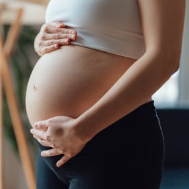 Side view close-up of pregnant woman touching her belly. 