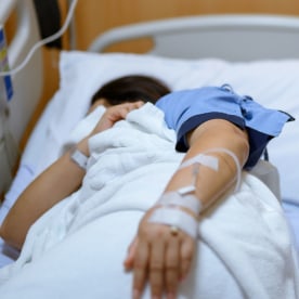 A patient lies on a bed with a mask in the recovery room in the hospital department.